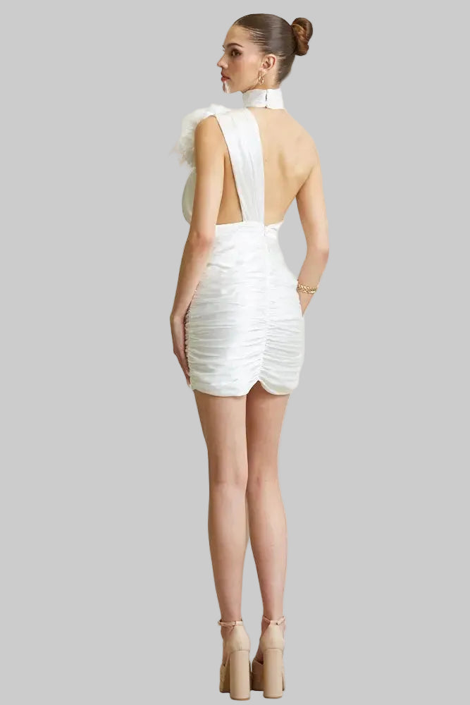 Woman wearing a white dress with a cut-out back design against a plain background